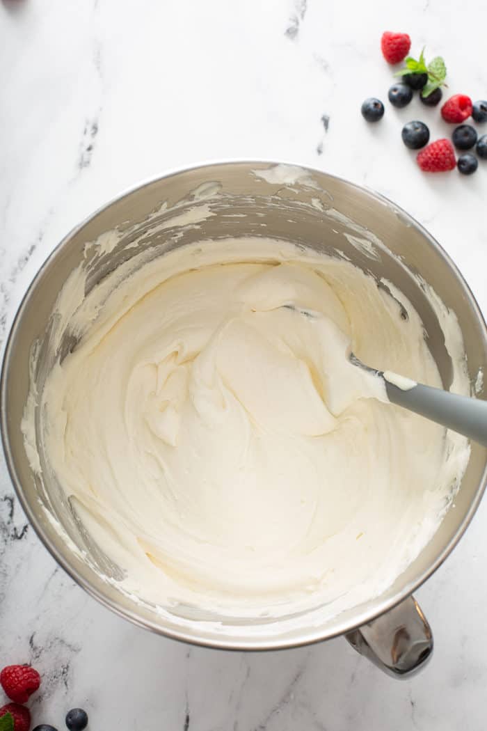 Filling for no-bake frozen cheesecake being stirred with a spatula in a metal mixing bowl