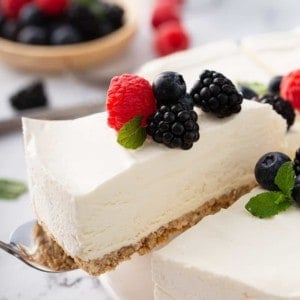 Pie server pulling a slice of no-bake frozen cheesecake out of the full cheesecake