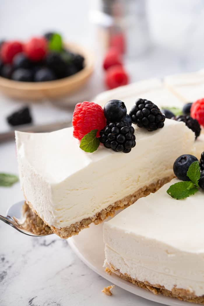 Pie server pulling a slice of no-bake frozen cheesecake out of the full cheesecake