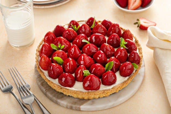 Cream cheese tart topped with whole strawberries and garnished with sprigs of mint.