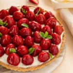 Strawberry tart, garnish with sprigs of mint, set on a marble serving platter.