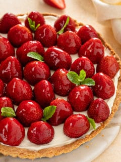 Strawberry tart, garnish with sprigs of mint, set on a marble serving platter.