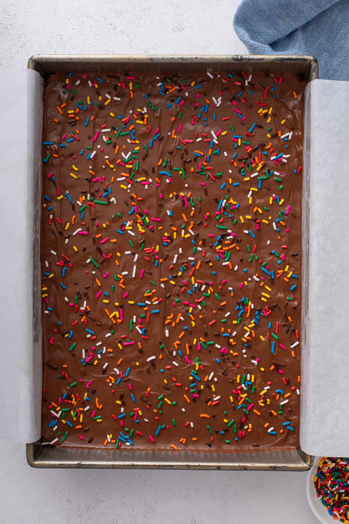 Scotcheroos assembled and topped with rainbow sprinkles in a baking pan.