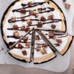 Sliced peanut butter pie topped with chocolate sauce and peanut butter cups.