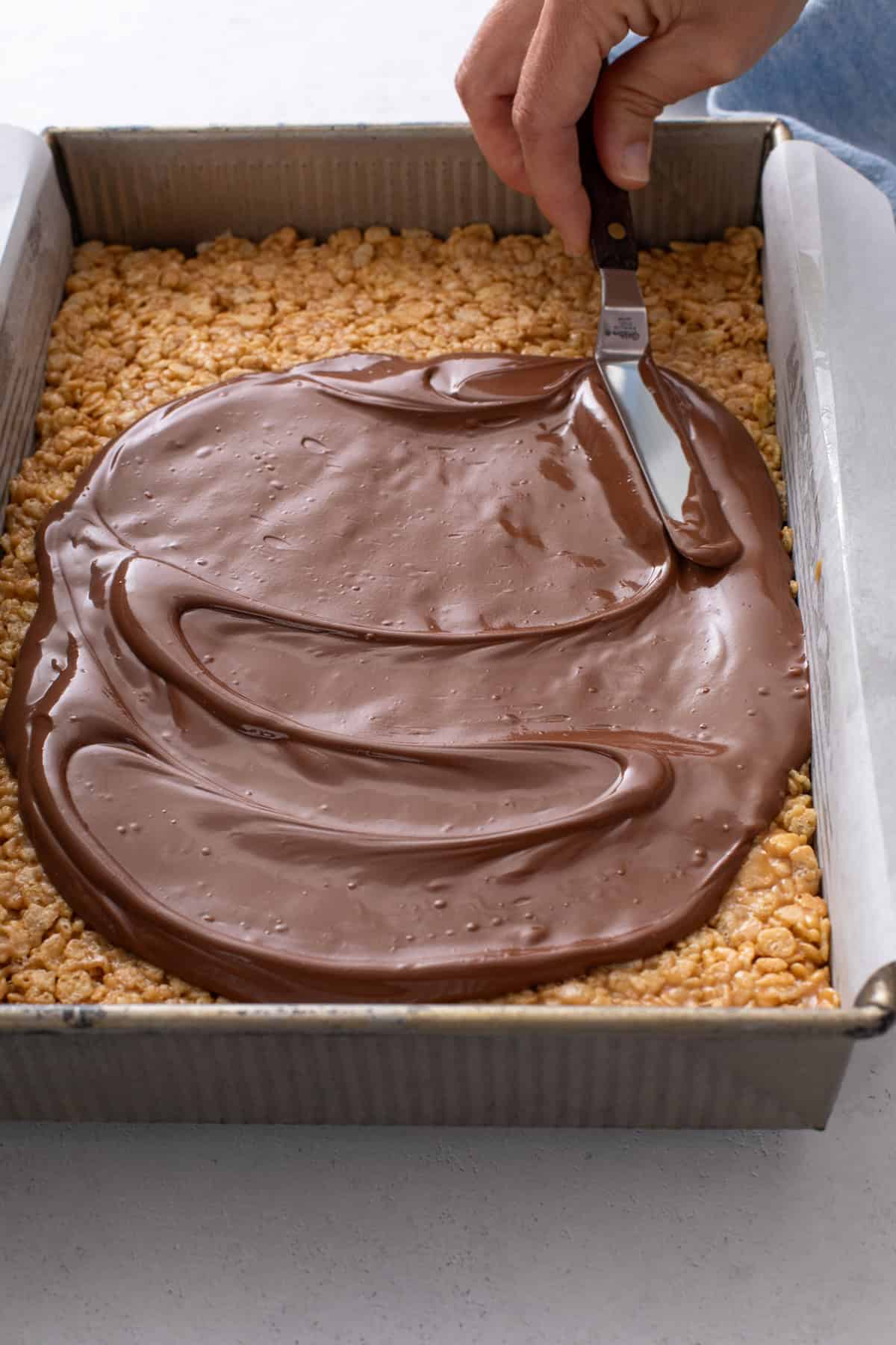 Melted chocolate and butterscotch chip mixture spread over the cereal base for scotcheroos.