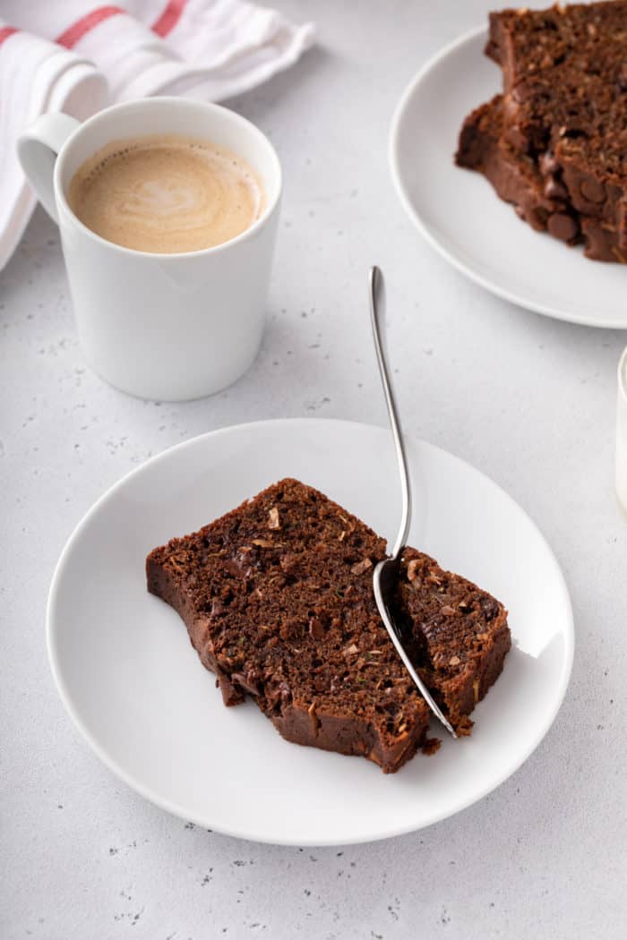 Fork taking a bite from the corner of a piece of chocolate zucchini bread.