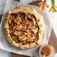 Baked apple galette on a wooden board next to a jar of salted maple glaze.