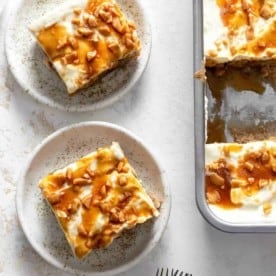 Slices of caramel apple poke cake on plates next to the full cake