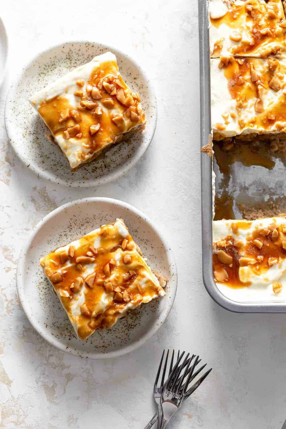 Slices of caramel apple poke cake on plates next to the full cake