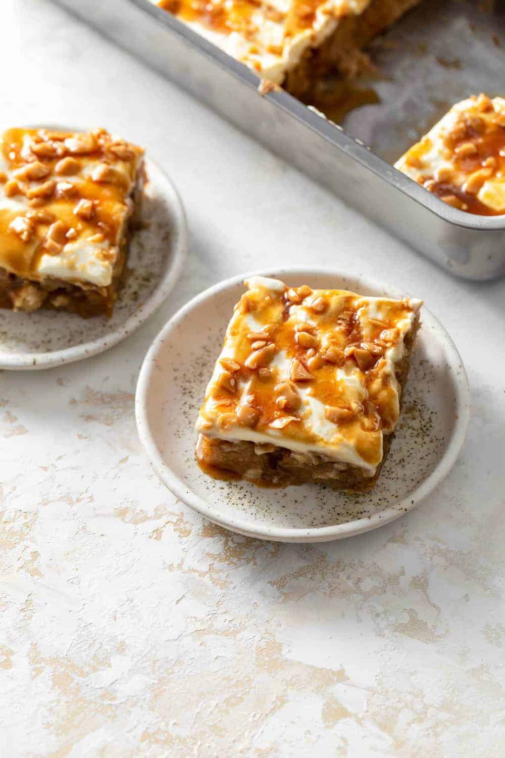 Plated slices of caramel apple poke cake, with full cake in the background