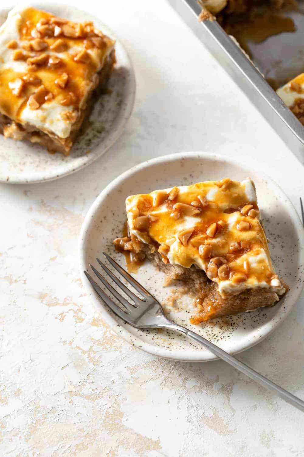 Slice of caramel apple poke cake on a plate, with several bites taken out of it