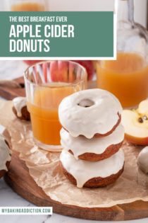 Three apple cider donuts stacked on a piece of parchment paper next to a glass of apple cider. Text overlay includes recipe name.