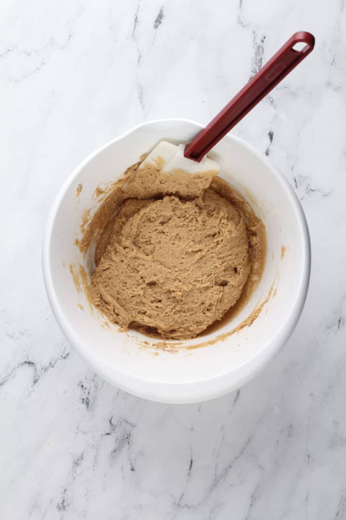 Dough for apple cider donuts in a white mixing bowl.