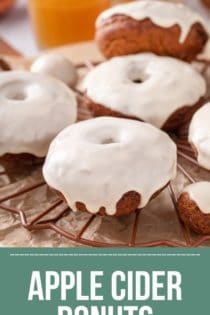 Several glazed apple cider donuts on a wire rack. Text overlay includes recipe name.