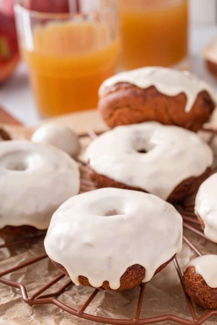 Several glazed apple cider donuts on a wire rack.