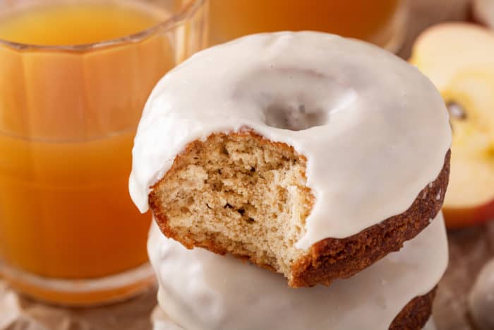 Close up of a bite taken from a glazed apple cider donut.