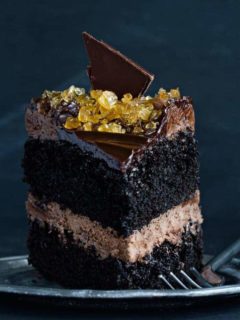 Close up slice of double chocolate salted caramel cake next to a fork on a plate