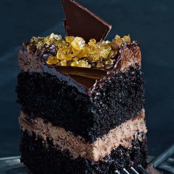 Close up slice of double chocolate salted caramel cake next to a fork on a plate