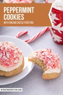 Cream cheese frosted peppermint cookie with a bite taken out of it leaning against a white plate holding a second peppermint cookie. Text overlay includes recipe name.