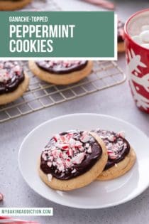 Two ganache-topped peppermint cookies on a white plate, with a wire rack of cookies in the background. Text overlay includes recipe name.