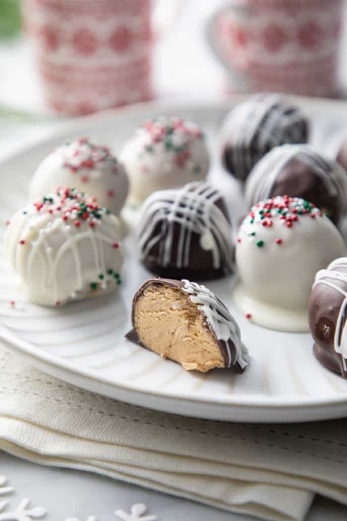 A halved chocolate-covered peanut butter ball on a white plate, surrounded by more chocolate-covered peanut butter balls.