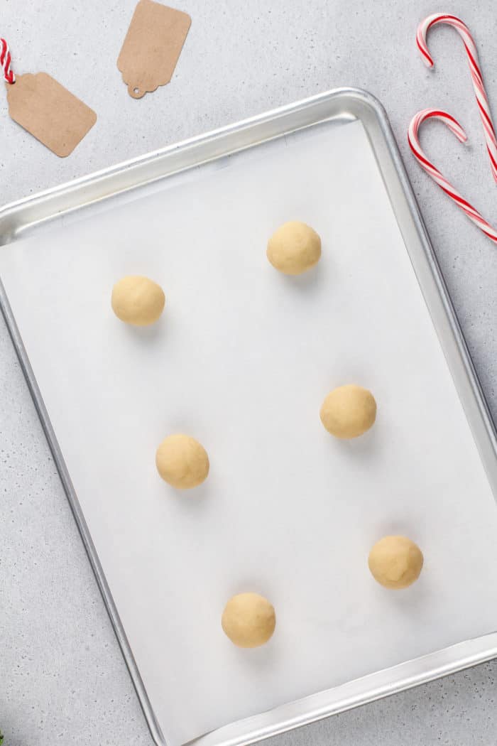 Balls of peppermint cookie dough on a parchment-lined baking sheet.