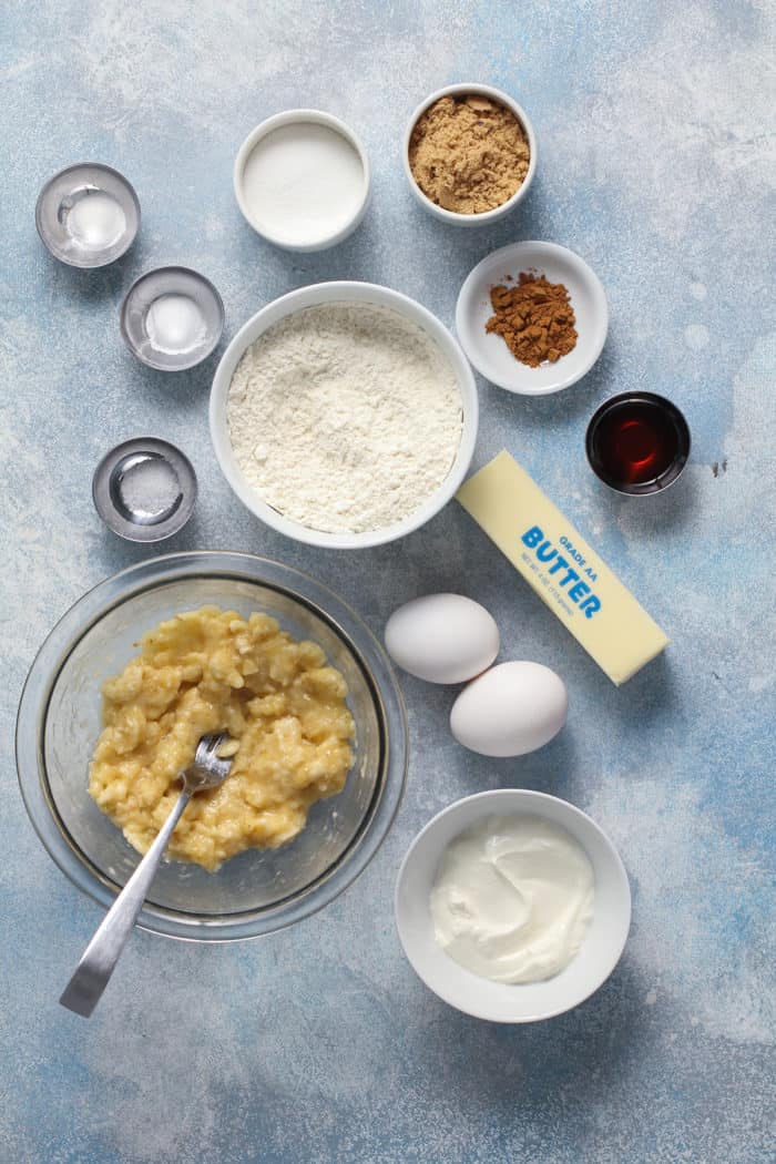 Ingredients for banana cupcakes arranged on a light blue countertop