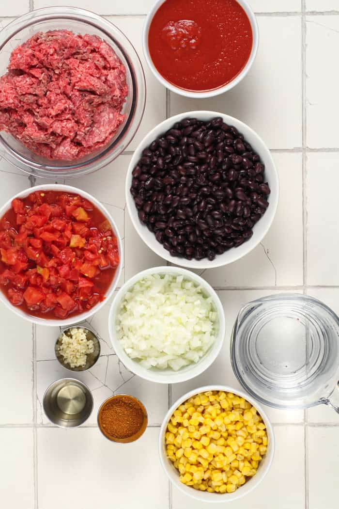 Ingredients for crockpot taco soup arranged on a white tiled countertop