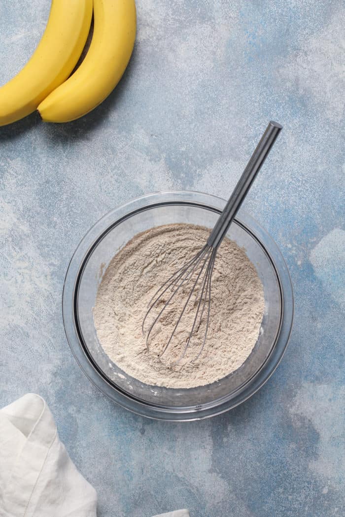 Dry ingredients for cupcakes in a glass mixing bowl on a blue countertop