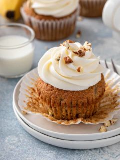 Banana cupcake that has been unwrapped set on a white plate.