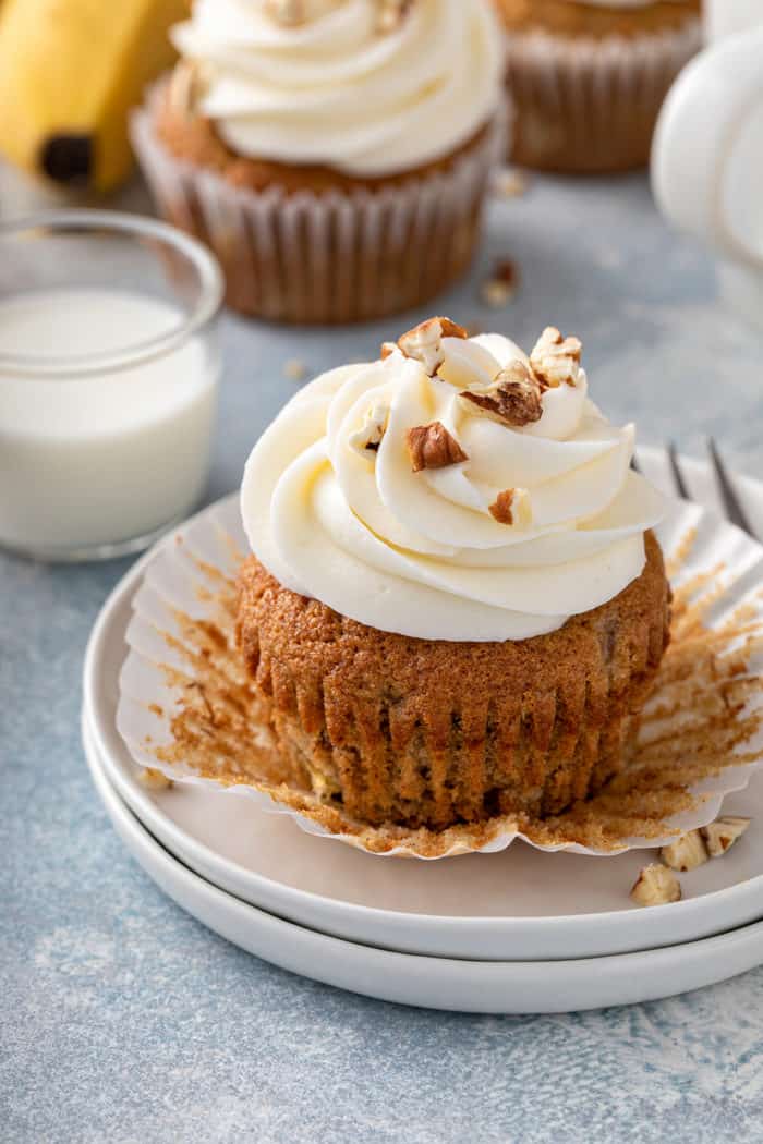 Banana cupcake that has been unwrapped set on a white plate. 