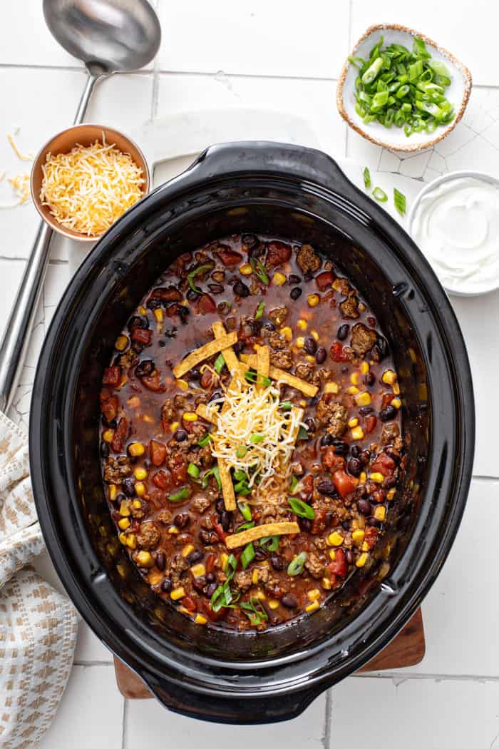 Overhead view of cooked taco soup in a crockpot, topped with cheese