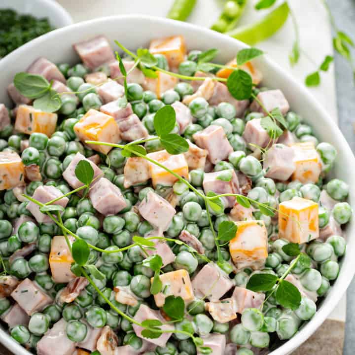 Close up of a bowl of Amish Pea Salad garnished with fresh herbs
