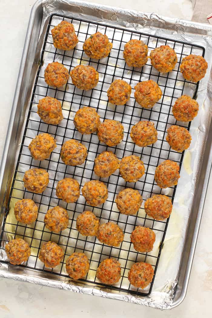 Baked sausage balls on a wire rack over a foil-lined pan