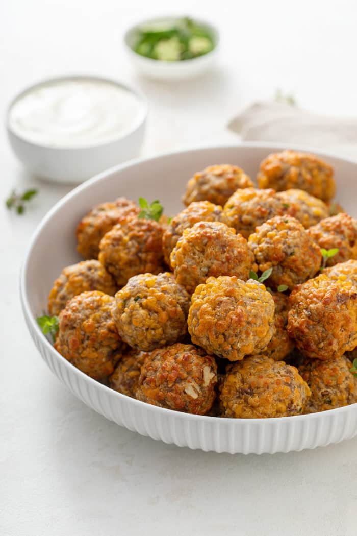 White bowl filled with sausage cheese balls. A bowl of ranch dip is in the background