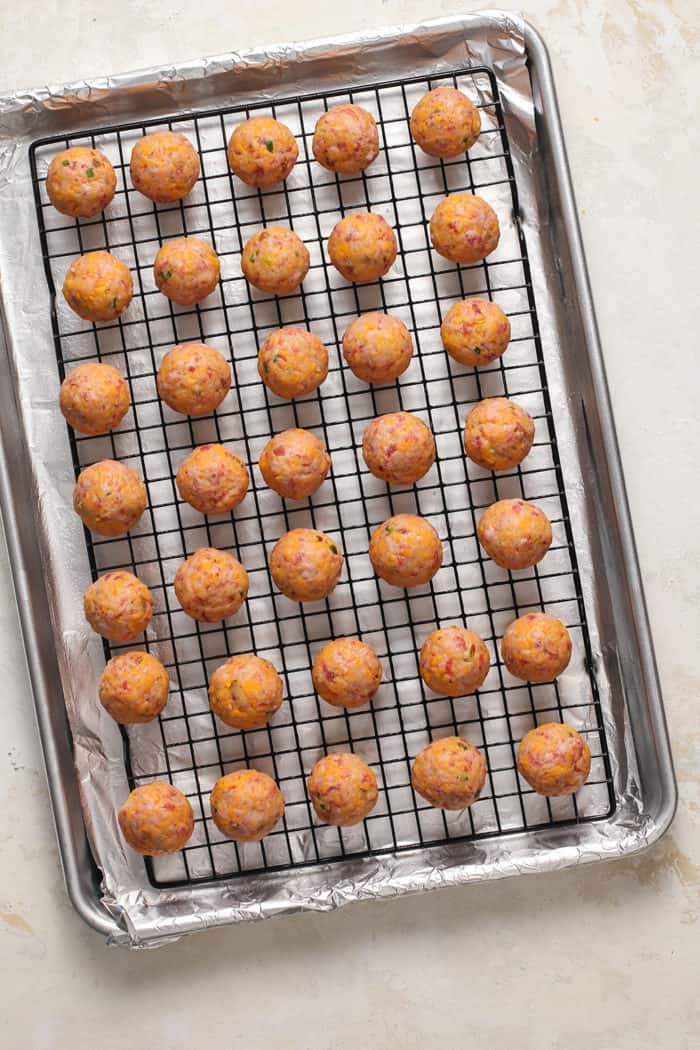 Shaped sausage balls on a wire rack set on top of a foil-lined sheet pan