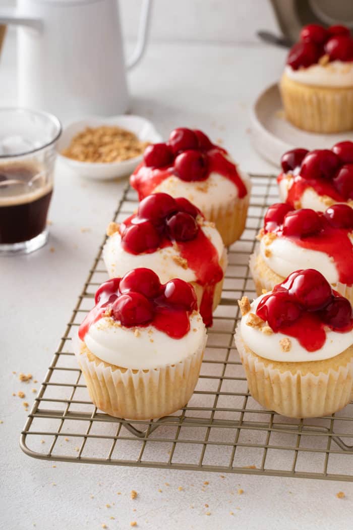 Cherry cheesecake cupcakes arranged on a wire cooling rack.