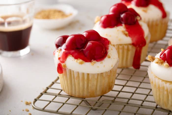 Close up of a cherry cheesecake cupcake on a wire cooling rack.