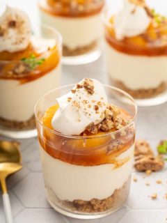 Four assembled peach peach cheesecakes on a white countertop
