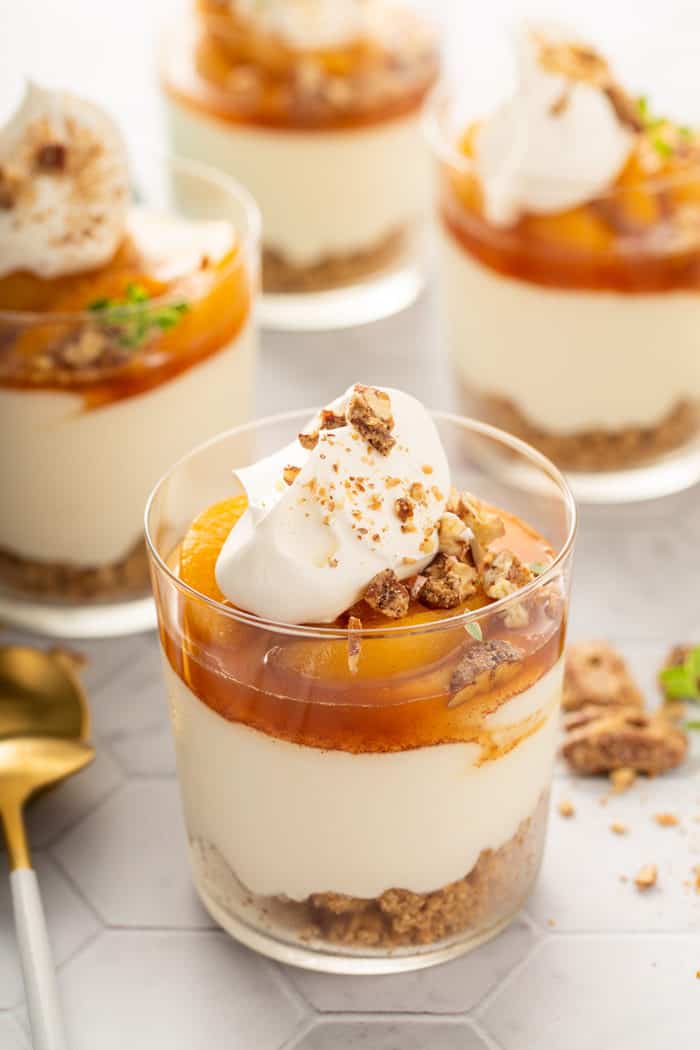 Four assembled peach peach cheesecakes on a white countertop