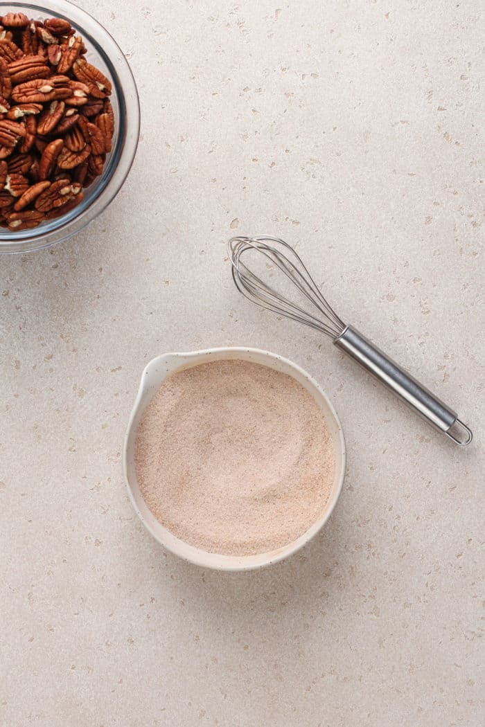 Small white bowl of cinnamon-sugar on a countertop.