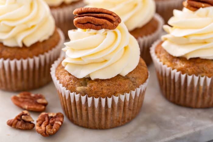 Close up of a frosted hummingbird cupcake topped with a pecan half