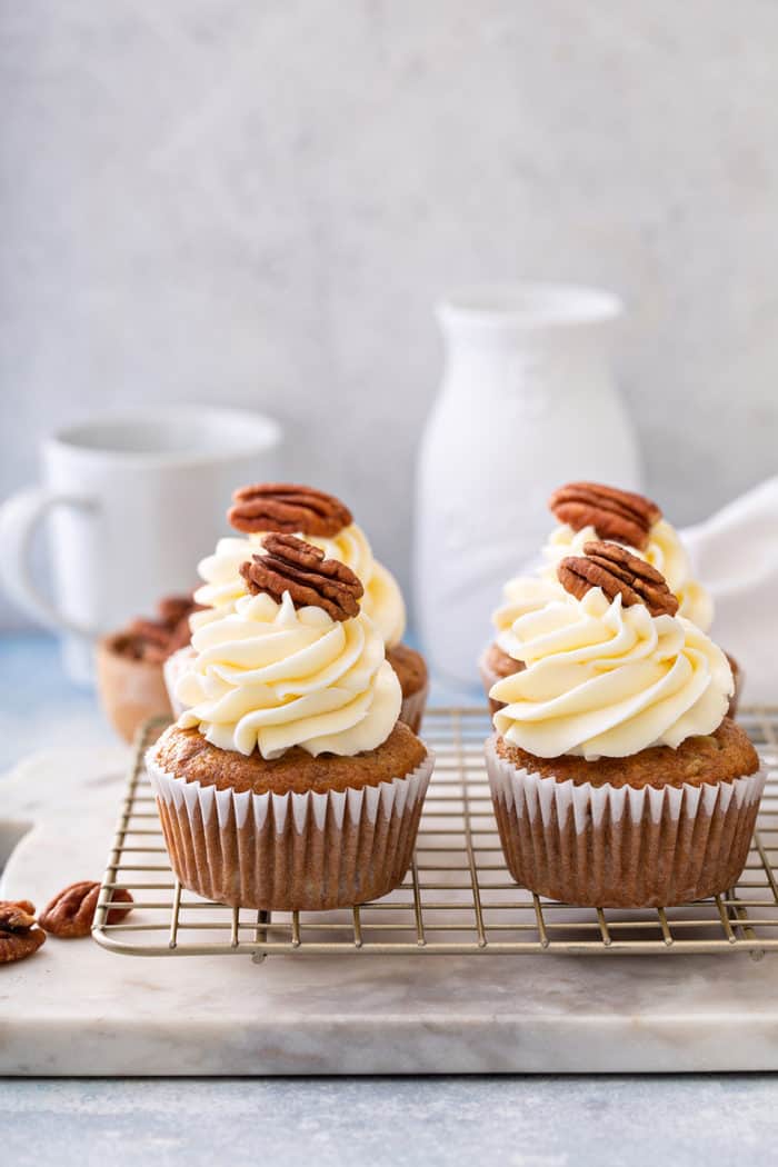 Four frosted hummingbird cupcakes set on a wire cooling rack