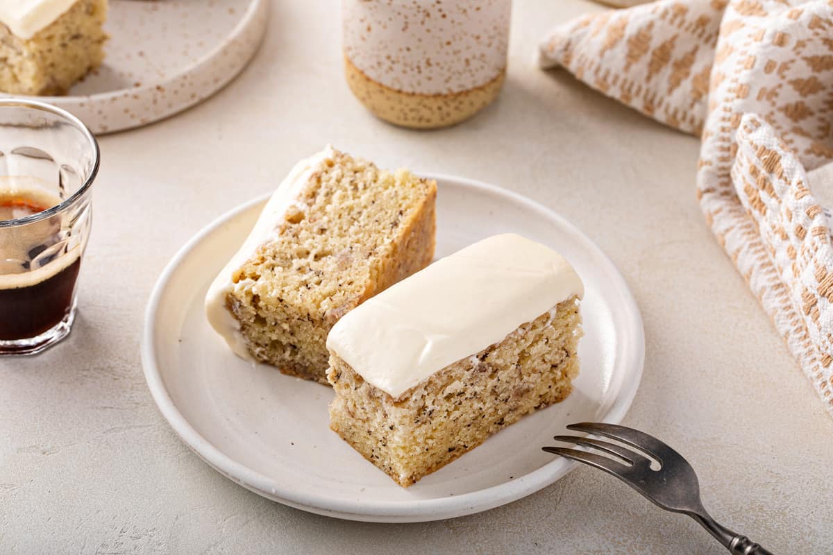 Halved slice of banana cake on a white plate. A fork is perched on the edge of the plate.