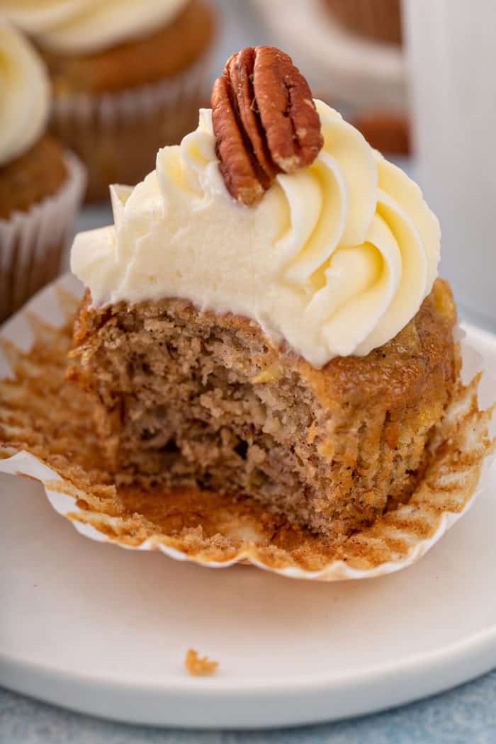 Unwrapped hummingbird cupcake with a bite taken out of it, set on a white plate