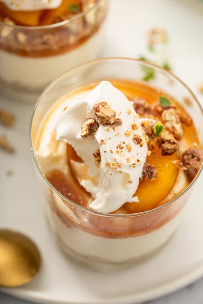 Close up of whipped topping and peach compote on top of a no-bake peach cheesecake