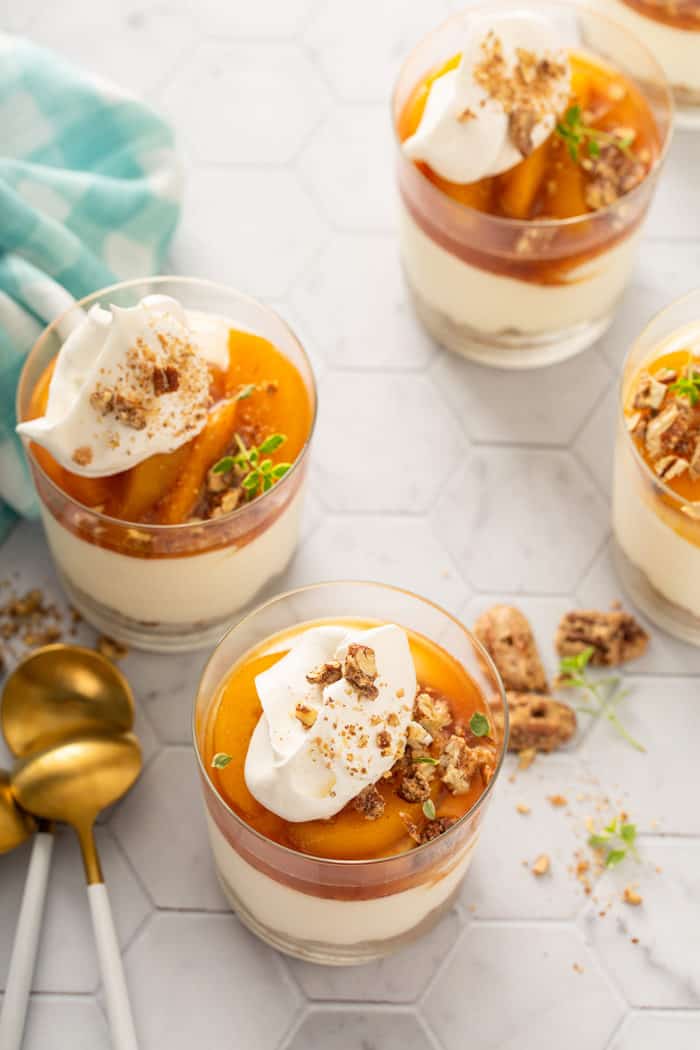 Several no-bake peach cheesecakes arranged on a white tiled countertop