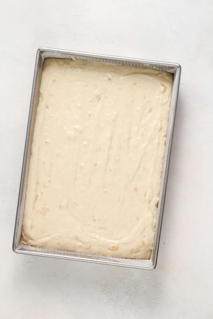 Banana cake batter spread into a cake pan, ready to be baked.