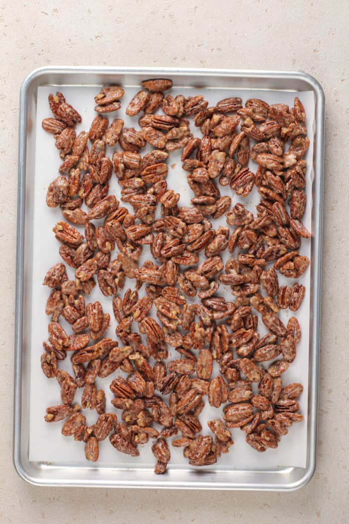 Unbaked candied pecans on a parchment-lined baking sheet, ready to go in the oven.