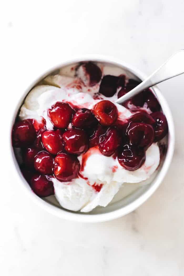 Homemade cherry pie filling on top of a bowl of ice cream